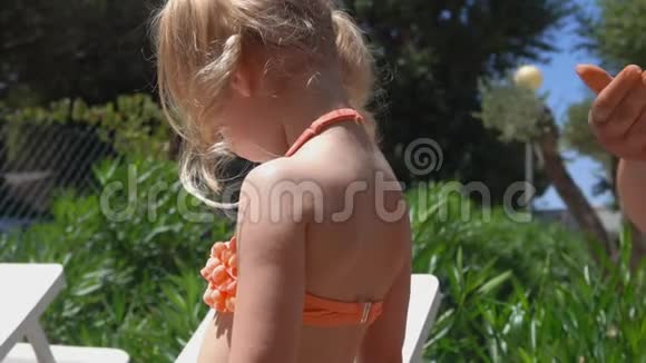 手在小女孩背上和肩膀上涂抹防晒霜视频的预览图