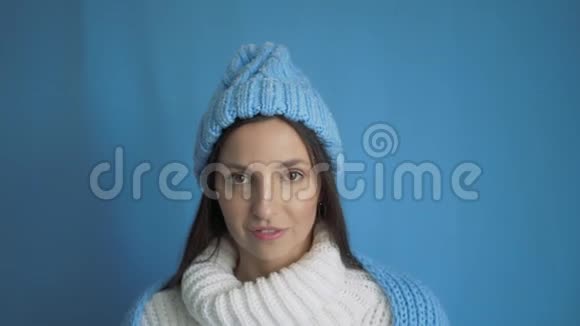 背景上穿着白色毛衣和蓝色帽子的女孩的肖像视频的预览图