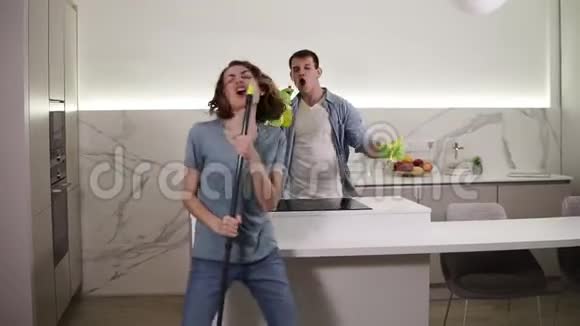 两个年轻人一起跳舞用扫帚和清洁工具当麦克风唱歌视频的预览图