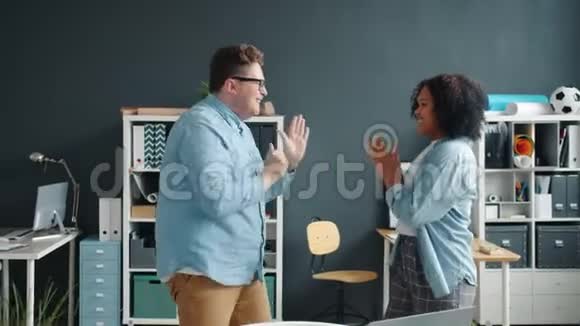 美国黑人女士和白人男子在办公室里手舞足蹈视频的预览图