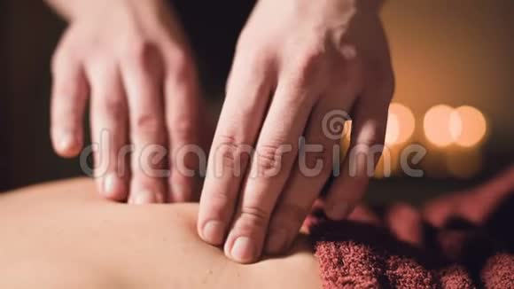 年轻的男性按摩治疗师正在按摩房间里的一个纹身的女人的背部做手指按摩的灯光视频的预览图