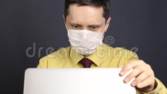 一个戴着医用面具的人打开一台笔记本电脑通过互联网参与交流手势广泛显示视频的预览图