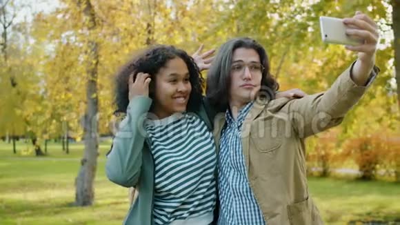 慢动作女孩和男人在公园里自拍拥抱玩手势视频的预览图