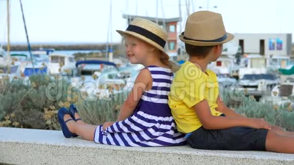 戴着草帽的小男孩和可爱的金发女孩坐着微笑视频的预览图