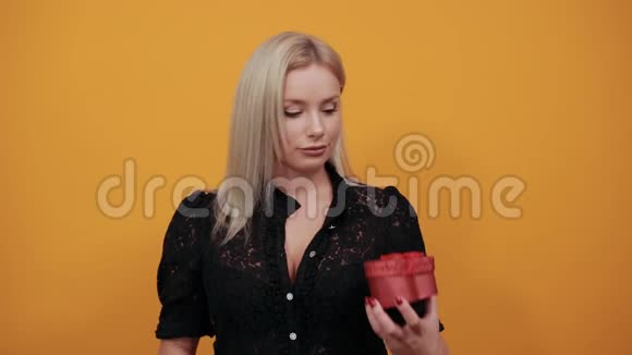 穿着黑色衣服的女孩快乐的女人以心形盒子的形式展示红色惊喜礼物视频的预览图