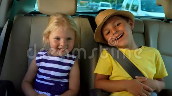 小男孩和小女孩正坐在车后座上开心地笑着视频的预览图