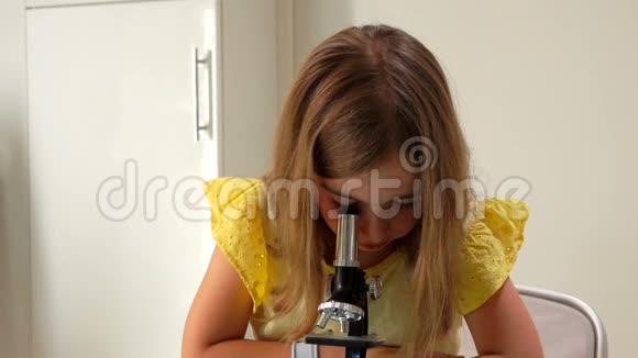 可爱的女孩正透过显微镜和照相机看着视频的预览图