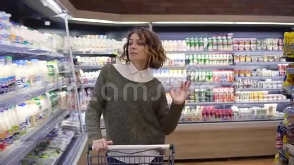 在超市里快乐的年轻女人在货架上的商品和奶制品中跳舞旋转玩得开心视频的预览图