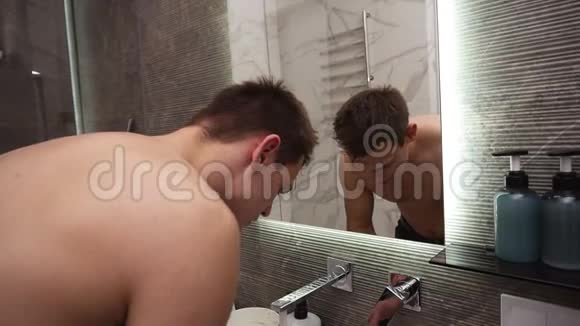 从水龙头里冒出来的冷水下无顶的帅哥在水槽里洗脸每天早晨打扫卫生视频的预览图