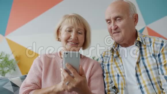 一对夫妇使用智能手机触摸屏幕在家里交谈视频的预览图