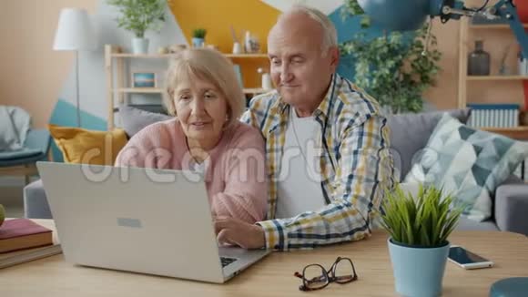 年长的女人和男人用手提电脑笑着笑着看着屏幕视频的预览图
