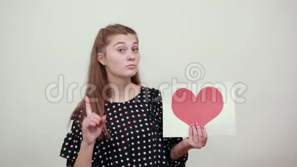 穿裙子的女孩拿着一张纸形状像红心和食指视频的预览图