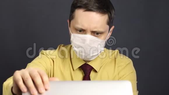一个戴着医疗面具的人打开笔记本电脑看新闻它用混乱的姿态惊恐地抬起头来他摇了摇他视频的预览图