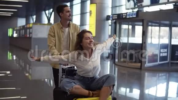 在机场的浪漫情侣迷人的年轻女子和英俊的男人带着手提箱准备旅行玩得开心视频的预览图