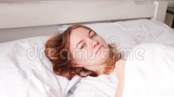 年轻的金发女孩正在床上睡觉白色床上用品早上好梦想概念视频的预览图