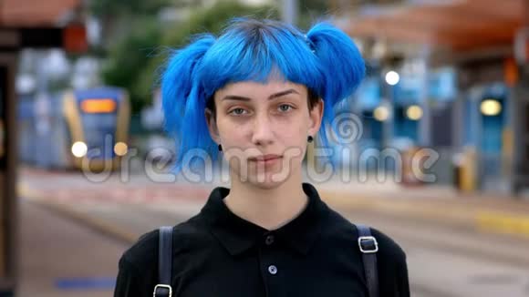 黄昏时分在城市街头的电车站年轻的蓝发女性戴着时尚的医用口罩视频的预览图