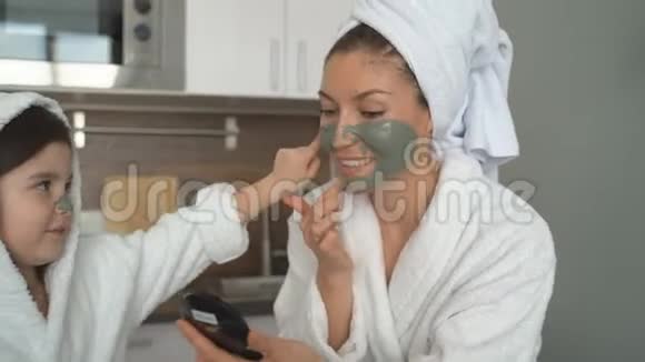 小女孩帮妈妈在脸上戴了一个黏土面具穿着睡衣的妈妈和女儿用面具做脸视频的预览图