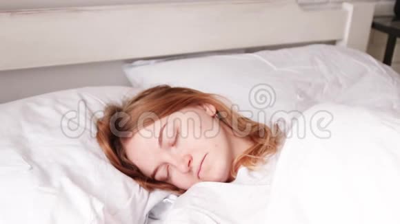 年轻的金发女孩睡在床上梦想概念视频的预览图