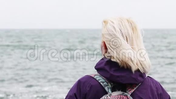 成年金发女人背对着远处的大海视频的预览图