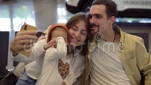 年轻的家庭在等飞机时用智能手机自拍一家人在国际机场等飞机视频的预览图