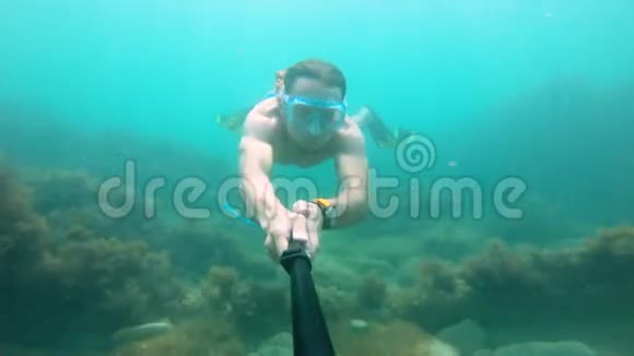 戴面具的肌肉男在水下游泳拿着相机在前面特写镜头视频的预览图