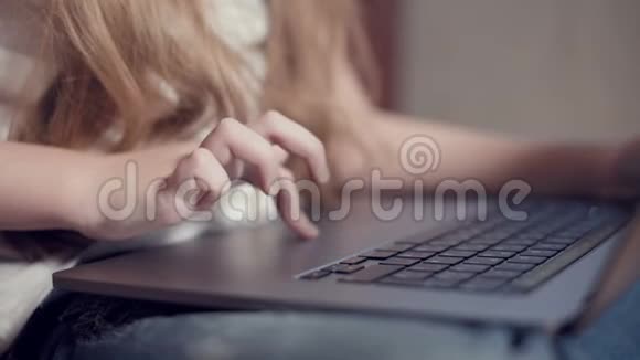 在笔记本电脑键盘上一个小女孩的手特写了一个浅浅的景深利用年轻一代的概念视频的预览图