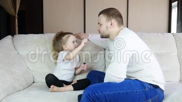 男人在家和他可爱的小女孩在一起女儿正在给爸爸化妆视频的预览图