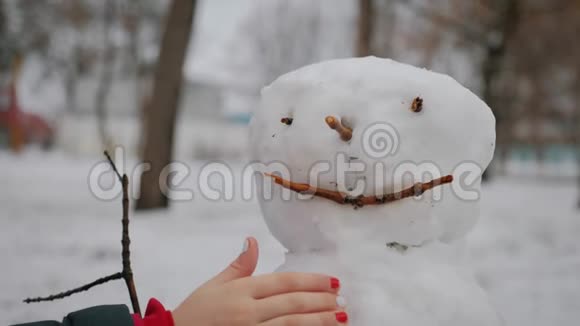 快乐女孩在冬季公园堆雪人寒假和圣诞节的概念视频的预览图