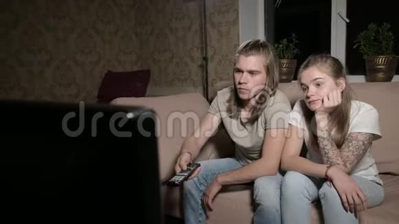 年轻夫妇正在看电视人用遥控器切换通道特写视频的预览图