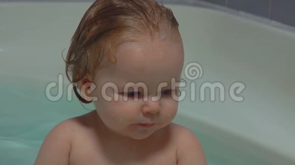 一个头发湿漉漉的快乐小宝宝坐在浴缸里泼水视频的预览图