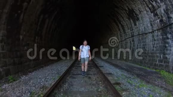 带着辫子和短裤的女孩沿着一条古老的石头铁路隧道走慢节奏视频的预览图