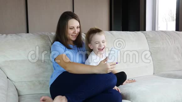 一家人的妈妈和小女儿在沙发上用智能手机玩得开心视频的预览图