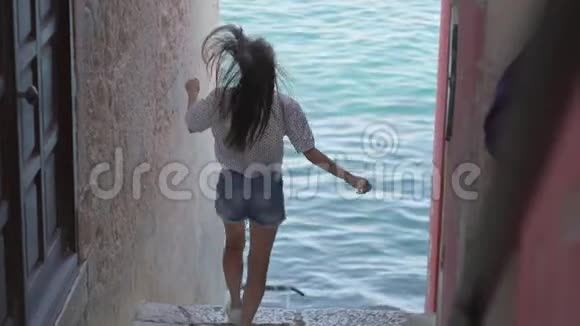 女人从楼梯上跑下来在小巷里跑向大海视频的预览图