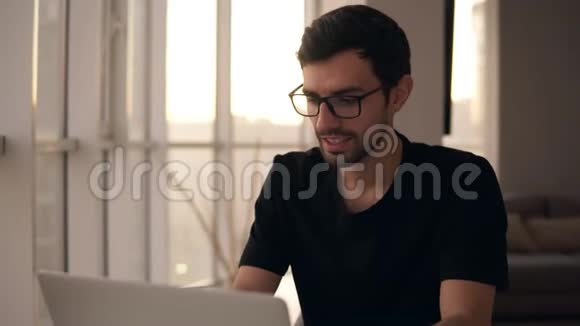 在远程工作场所慢动作使用笔记本电脑的快乐男人的肖像家庭电脑自由职业者视频的预览图