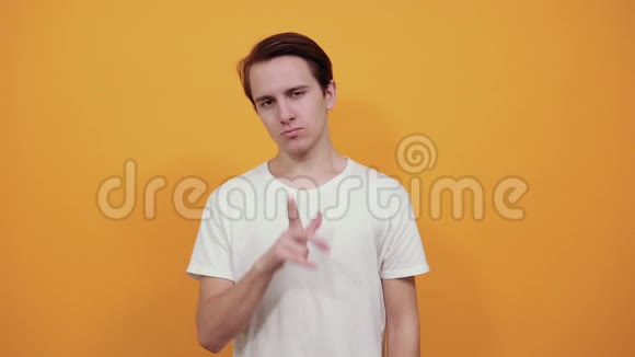 一个穿白色衣服的男人要求沉默把手指放在黄色背景上的嘴唇上视频的预览图