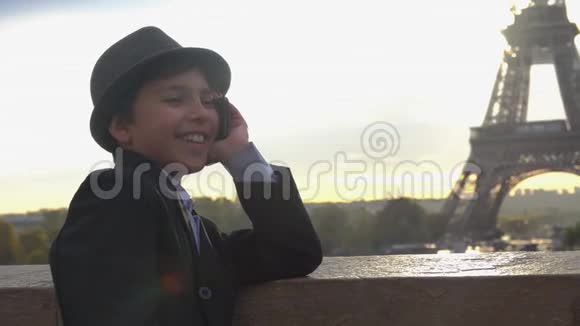 十几岁的男孩正在埃菲尔铁塔的背景上打电话视频的预览图