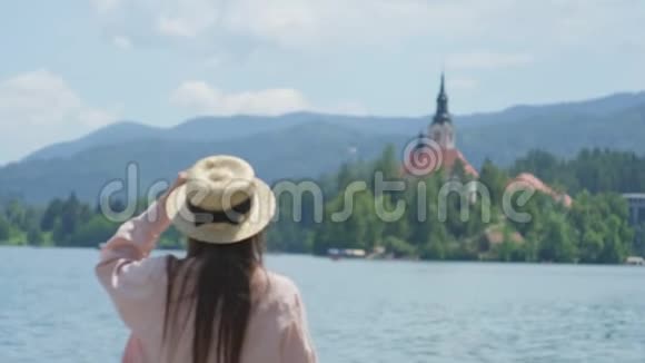 受启发的妇女在斯洛文尼亚的布莱德湖旁摊手视频的预览图