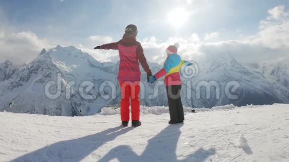 母亲和女儿享受旅程在滑雪场穿着冬装的幸福家庭冬天的时候看着视频的预览图