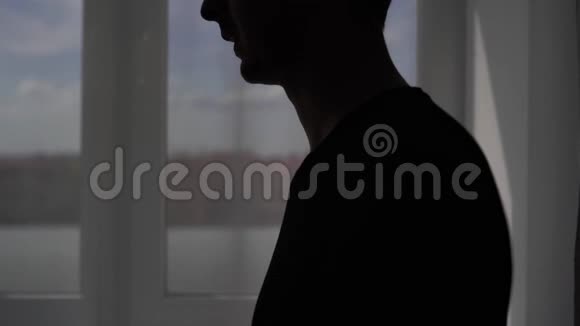 窗户背景上一个咳嗽男人的剪影病人在家接受科维德病毒治疗视频的预览图