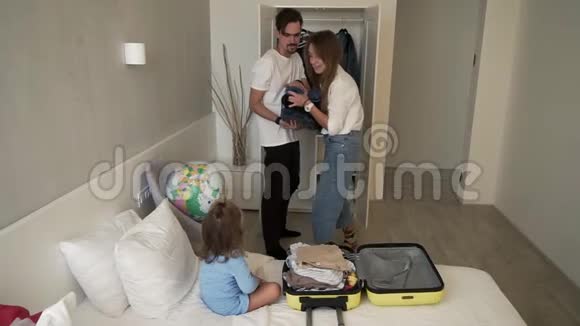 年轻的现代白种人夫妇准备和他们的小女儿一起旅行带着手提箱玩得开心微笑着视频的预览图