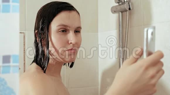 女孩洗澡用电话女人一边看社交网络的新闻一边站在水流下视频的预览图