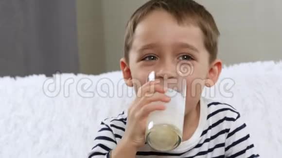 一个迷人的小男孩喝酸奶牛奶从玻璃玻璃胡子从牛奶上婴儿的脸孩子视频的预览图