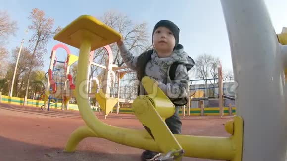 一个可爱的小男孩在公园的操场上玩耍花时间在户外很有趣视频的预览图