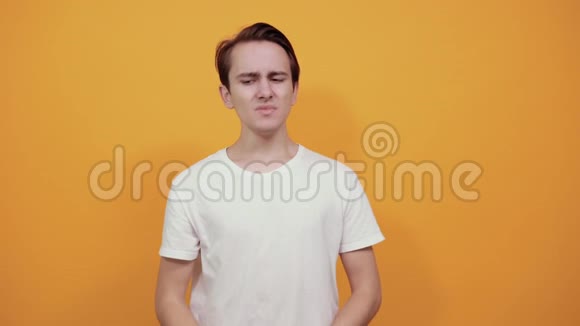 胃痛胃病白色T恤年轻男性黄色背景视频的预览图