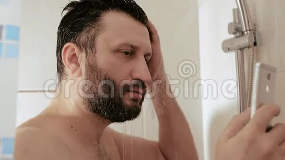 一个拿着电话洗澡的人一个留胡子的家伙在看电话里的新闻时在水下洗头互联网视频的预览图
