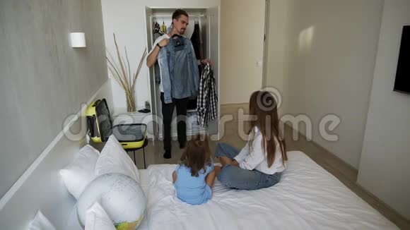 一个英俊的留着胡子的男人向妻子和小女儿请教穿哪件衬衫视频的预览图
