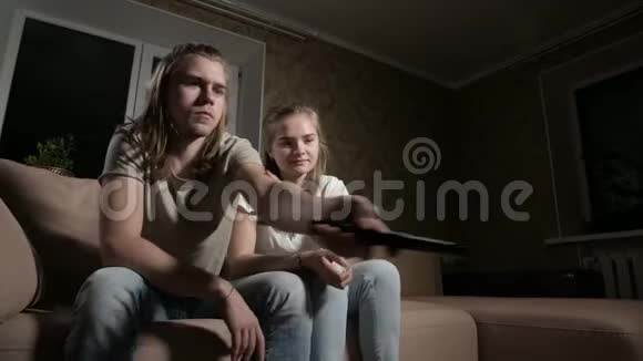年轻夫妇正在看电视男人切换频道女人选择控制视频的预览图