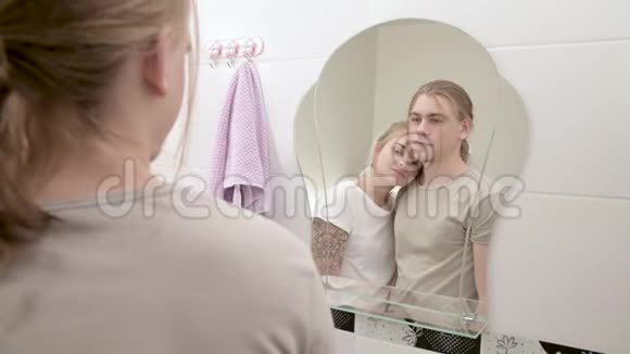 这对年轻夫妇站在白色的浴室里对着镜子看倒影视频的预览图