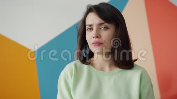 昏昏欲睡的女人打哈欠的慢动作看着站在彩色背景上的摄像机视频的预览图