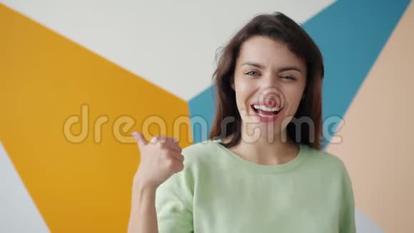幸福的年轻女士在五颜六色的背景下竖起大拇指的肖像视频的预览图